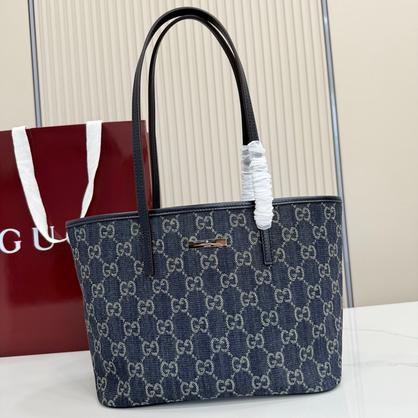Generation Gucci系列深入探索品牌典藏元素，将不同世代的设计融合成一种美学叙事。GG牛仔布为精致廓形增添品牌标志性元素。这款托特包通过品牌标识徽饰将日常风格提升至新高度，内部配有拉链口袋。
