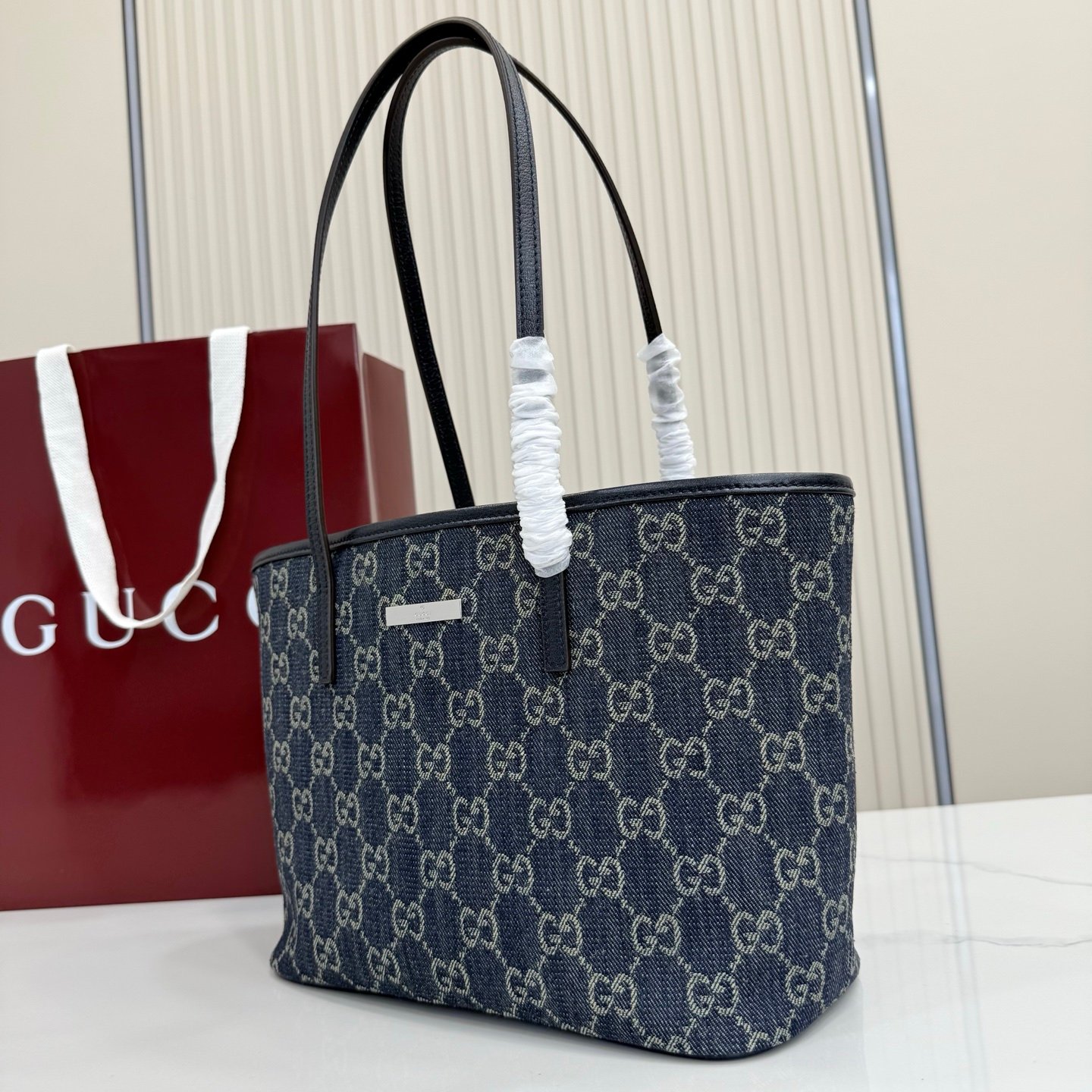 Generation Gucci系列深入探索品牌典藏元素，将不同世代的设计融合成一种美学叙事。GG牛仔布为精致廓形增添品牌标志性元素。这款托特包通过品牌标识徽饰将日常风格提升至新高度，内部配有拉链口袋。