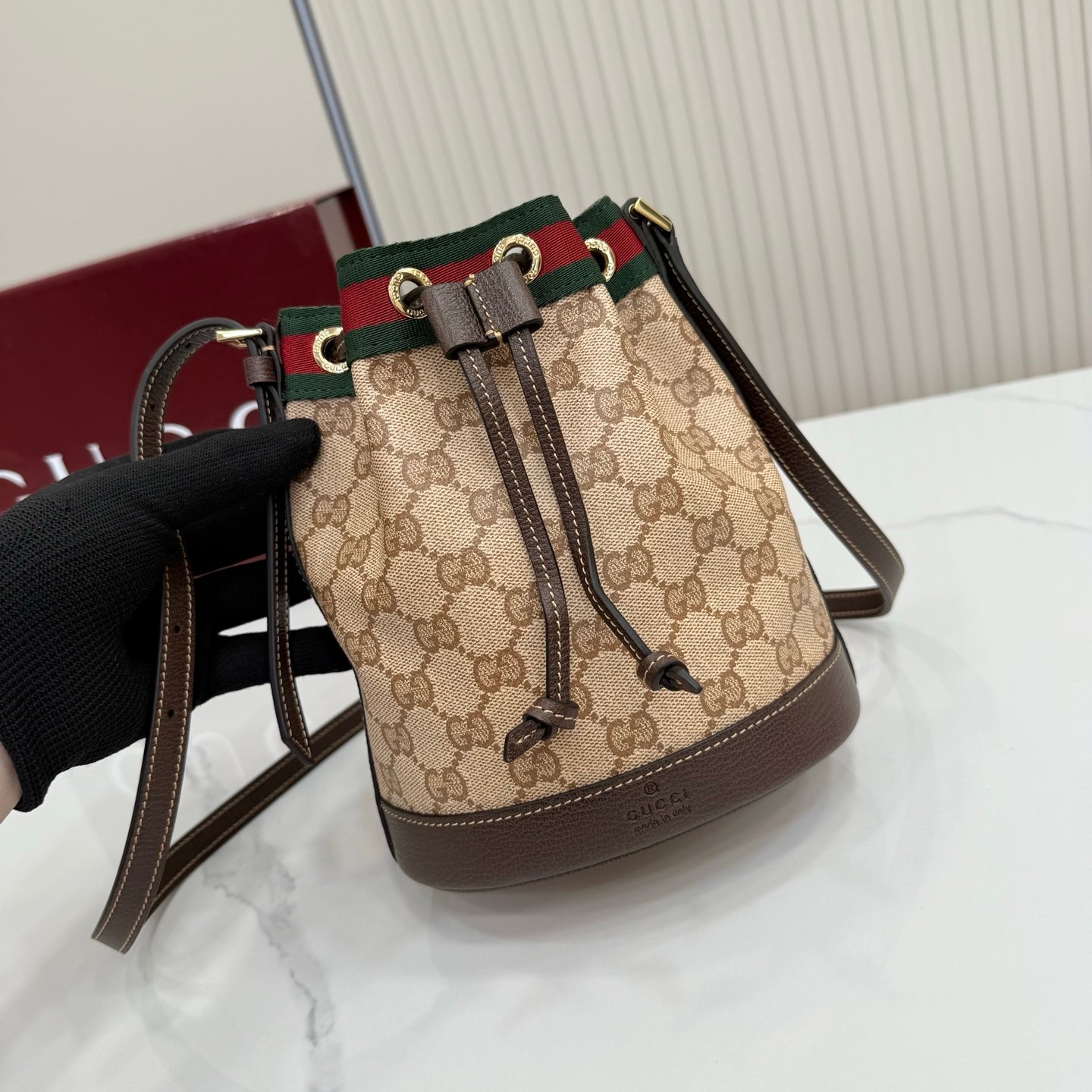 Generation Gucci古驰世代系列深入探索品牌的典藏元素，将不同世代的设计融合为统一的美学叙事。GG涂层帆布搭配经典织带，为多功能小型皮具带来标志性风格，如这款设计用于存放日常必需品的水桶包。