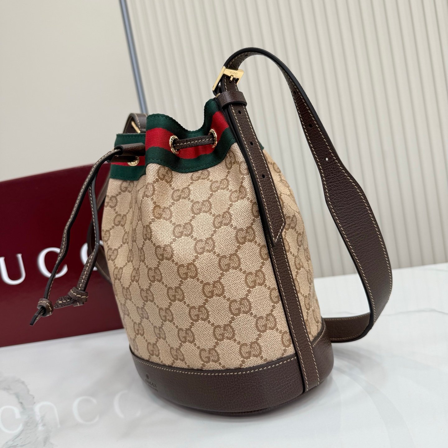 Generation Gucci系列深入探索品牌的经典元素，将不同世代的设计融合成一种美学叙事。GG涂层帆布搭配织带，为多功能小型皮具带来品牌标志性的设计，例如这款设计用于存放日常必需品的水桶包。