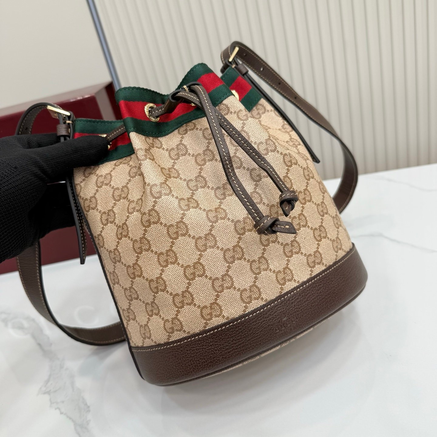 Generation Gucci系列深入探索品牌的经典元素，将不同世代的设计融合成一种美学叙事。GG涂层帆布搭配织带，为多功能小型皮具带来品牌标志性的设计，例如这款设计用于存放日常必需品的水桶包。