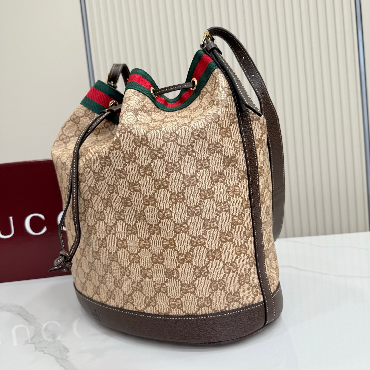 Generation Gucci系列深入探索品牌的经典元素，将不同世代的设计融合成一种美学叙事。GG涂层帆布搭配织带，为多功能小型皮具带来品牌标志性的设计，例如这款设计用于存放日常必需品的水桶包。