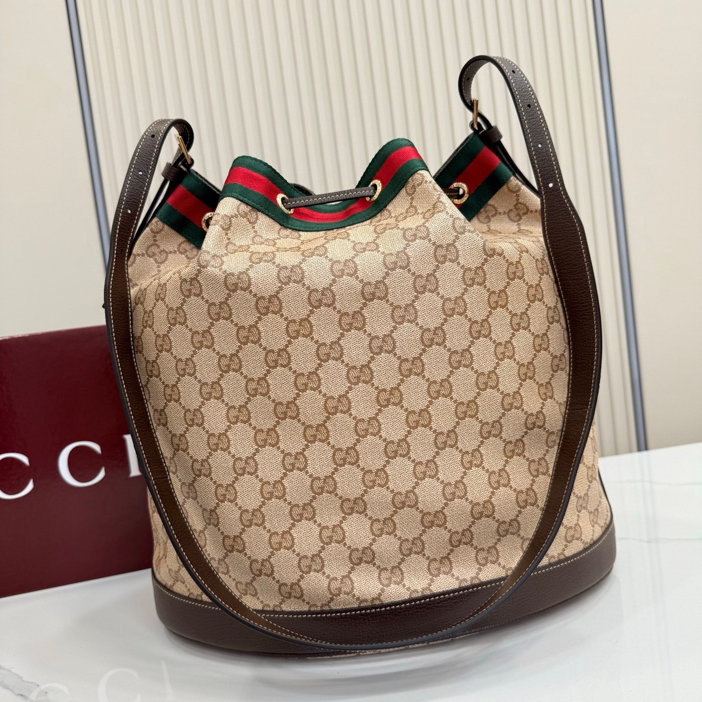 Generation Gucci系列深入探索品牌的经典元素，将不同世代的设计融合成一种美学叙事。GG涂层帆布搭配织带，为多功能小型皮具带来品牌标志性的设计，例如这款设计用于存放日常必需品的水桶包。