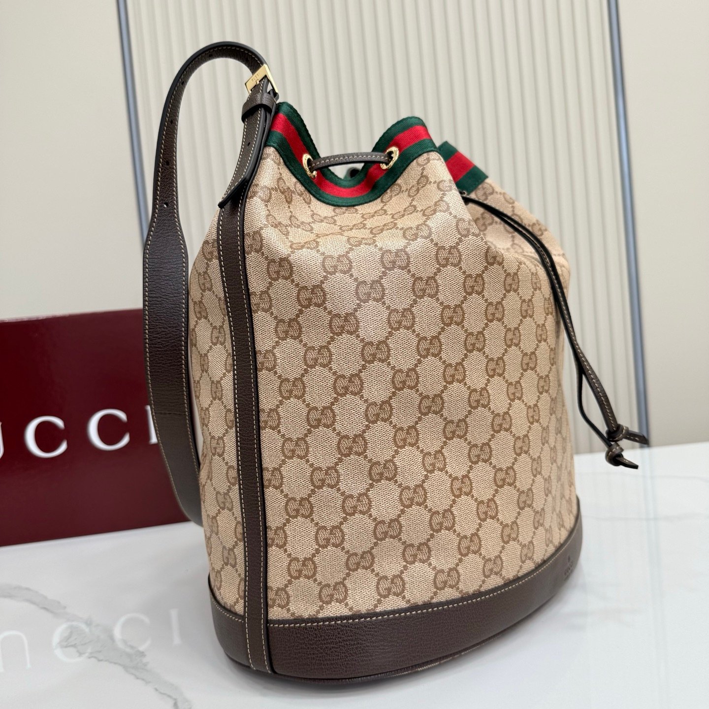 Generation Gucci系列深入探索品牌的经典元素，将不同世代的设计融合成一种美学叙事。GG涂层帆布搭配织带，为多功能小型皮具带来品牌标志性的设计，例如这款设计用于存放日常必需品的水桶包。