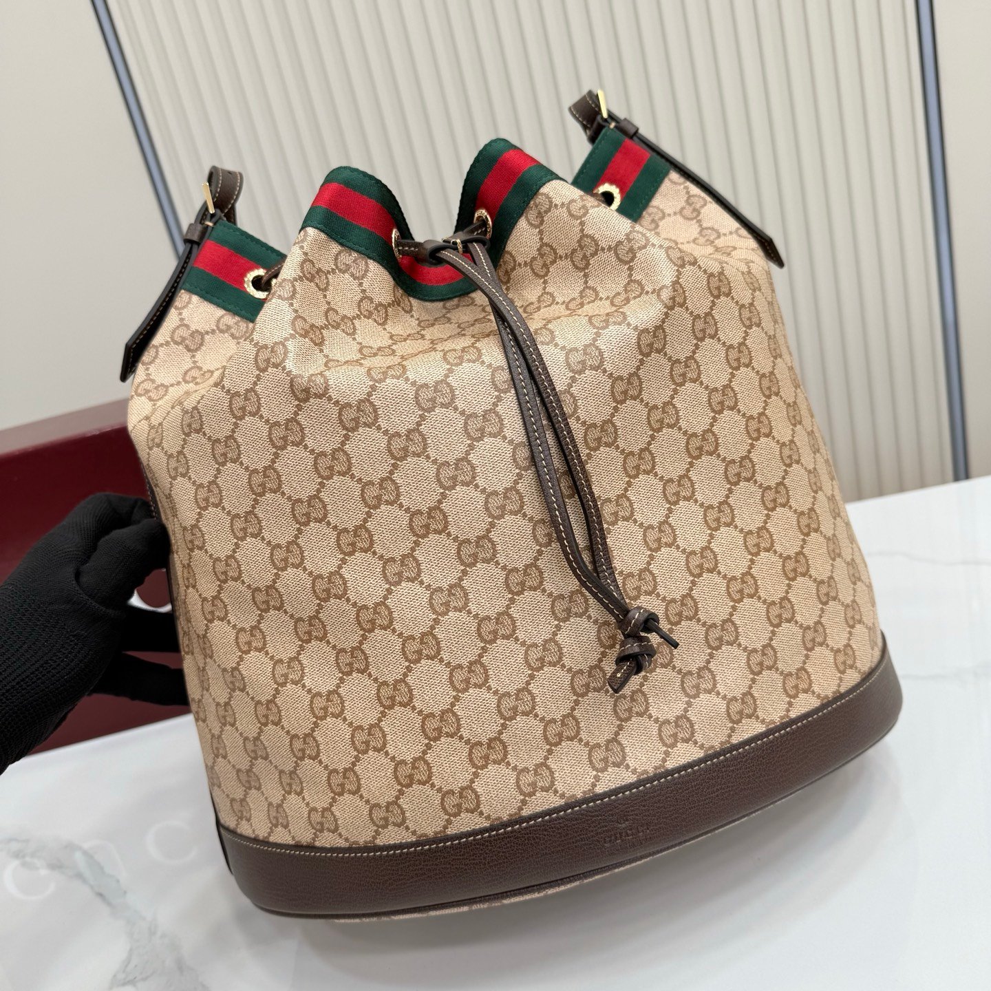 Generation Gucci系列深入探索品牌的经典元素，将不同世代的设计融合成一种美学叙事。GG涂层帆布搭配织带，为多功能小型皮具带来品牌标志性的设计，例如这款设计用于存放日常必需品的水桶包。