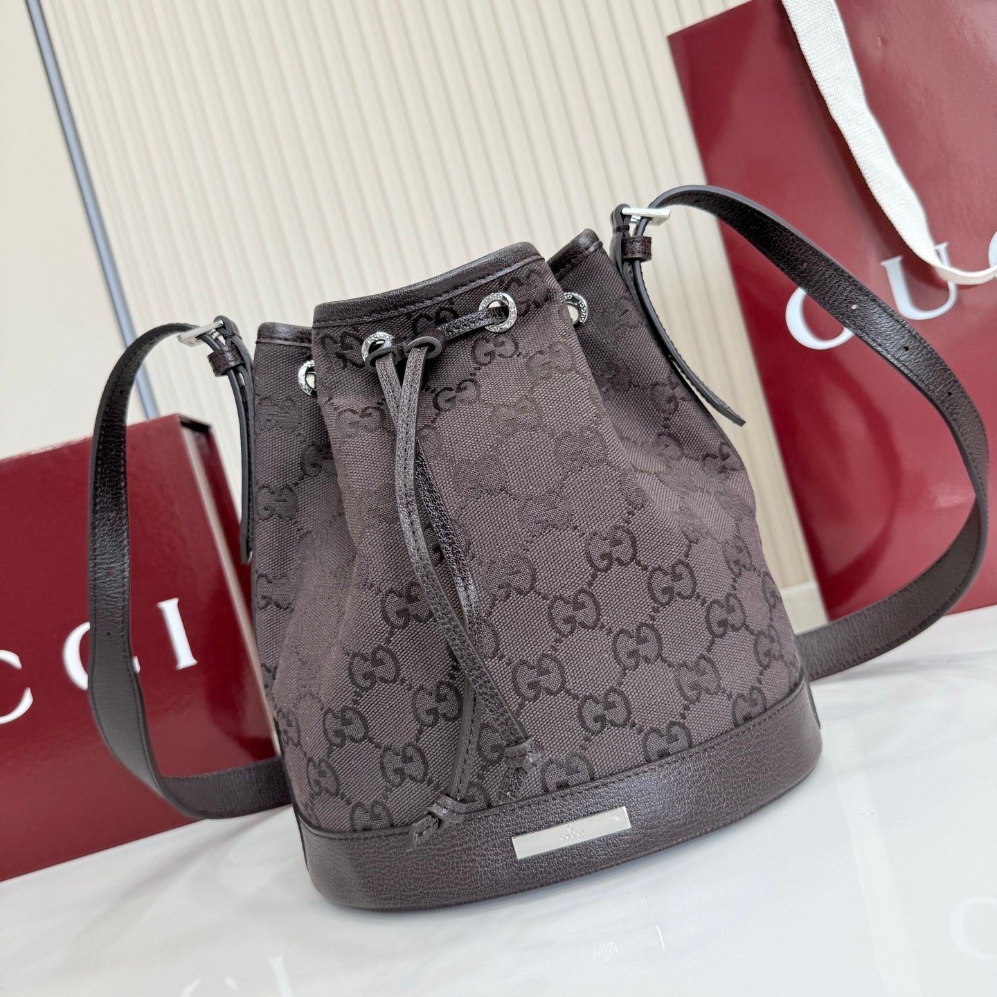 Generation Gucci系列深入探索品牌的典藏元素，将不同世代的设计融合成一种美学叙事。GG深棕色帆布为多功能小型皮具带来品牌标志性的点缀，比如这款设计用于存放日常必需品的水桶包。