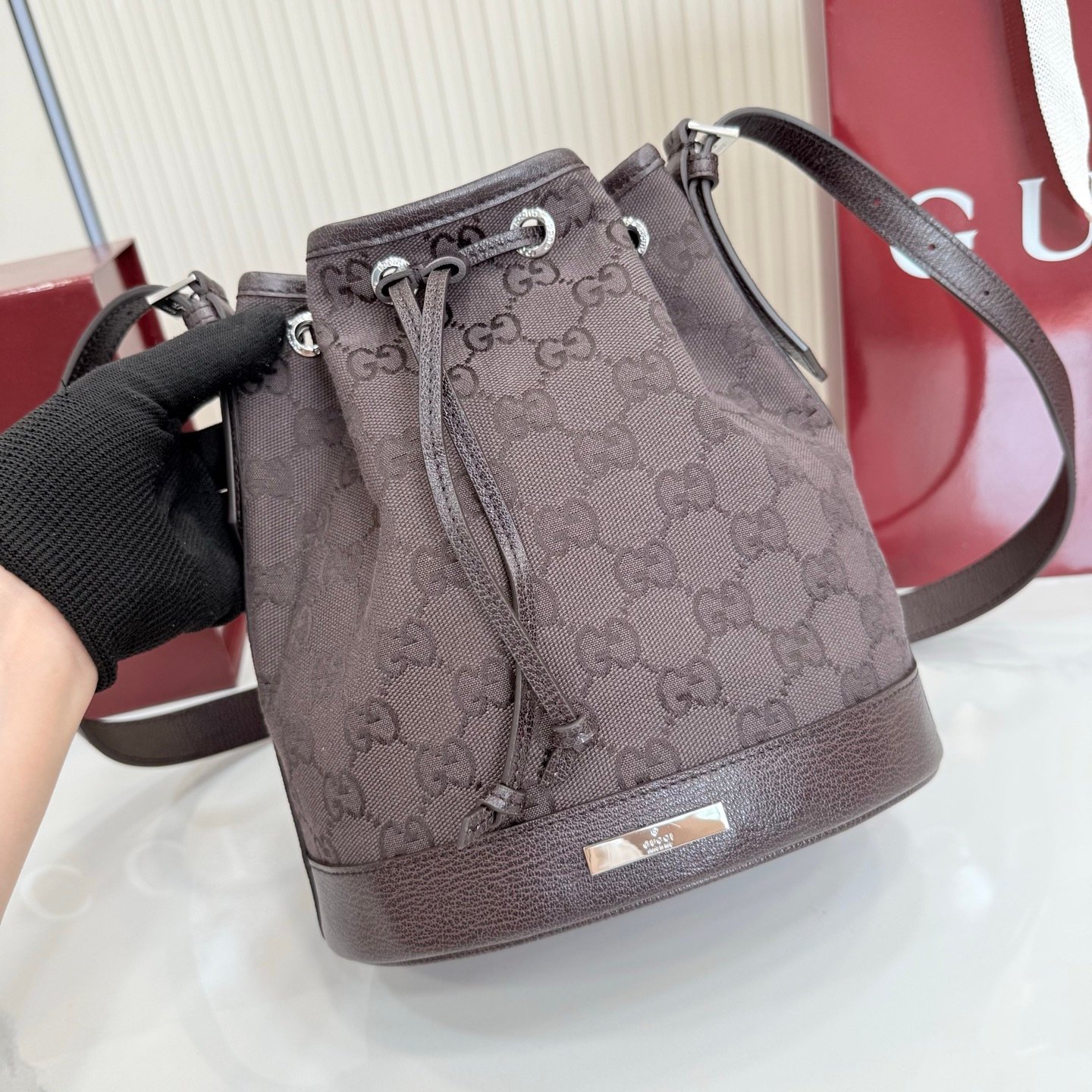 Generation Gucci系列深入探索品牌的典藏元素，将不同世代的设计融合成一种美学叙事。GG深棕色帆布为多功能小型皮具带来品牌标志性的点缀，比如这款设计用于存放日常必需品的水桶包。
