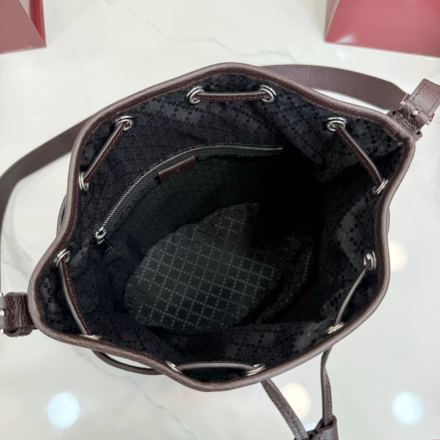 Generation Gucci系列深入探索品牌的典藏元素，将不同世代的设计融合成一种美学叙事。GG深棕色帆布为多功能小型皮具带来品牌标志性的点缀，比如这款设计用于存放日常必需品的水桶包。