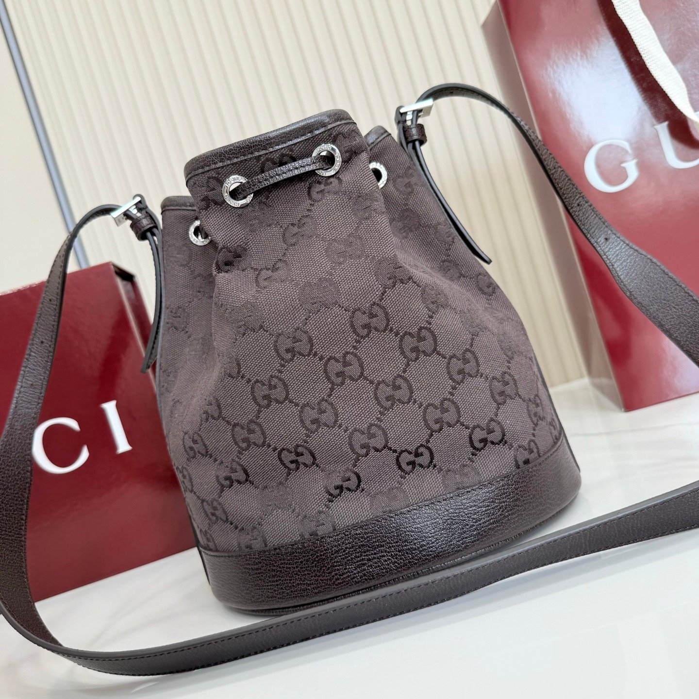Generation Gucci系列深入探索品牌的典藏元素，将不同世代的设计融合成一种美学叙事。GG深棕色帆布为多功能小型皮具带来品牌标志性的点缀，比如这款设计用于存放日常必需品的水桶包。