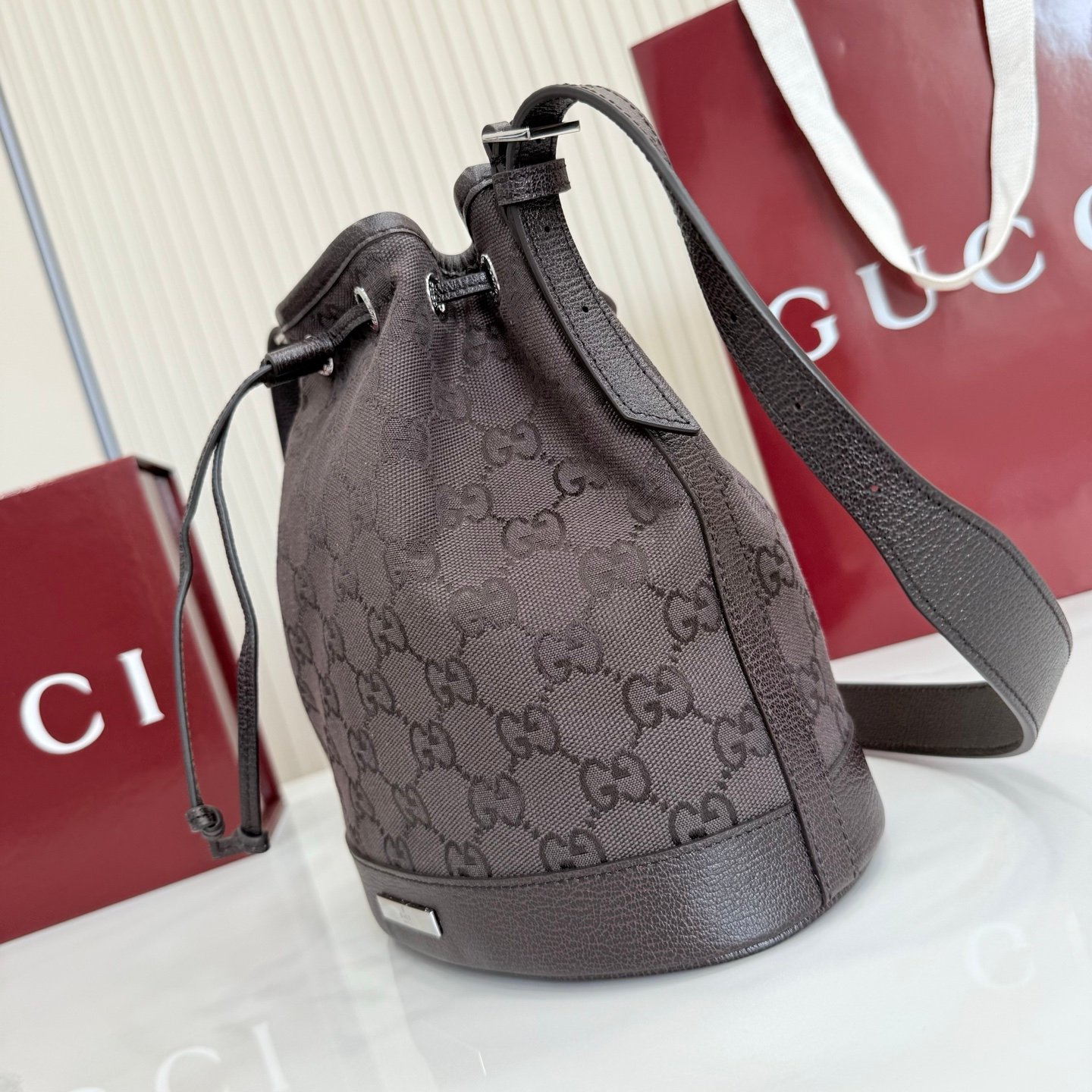 Generation Gucci系列深入探索品牌的典藏元素，将不同世代的设计融合成一种美学叙事。GG深棕色帆布为多功能小型皮具带来品牌标志性的点缀，比如这款设计用于存放日常必需品的水桶包。