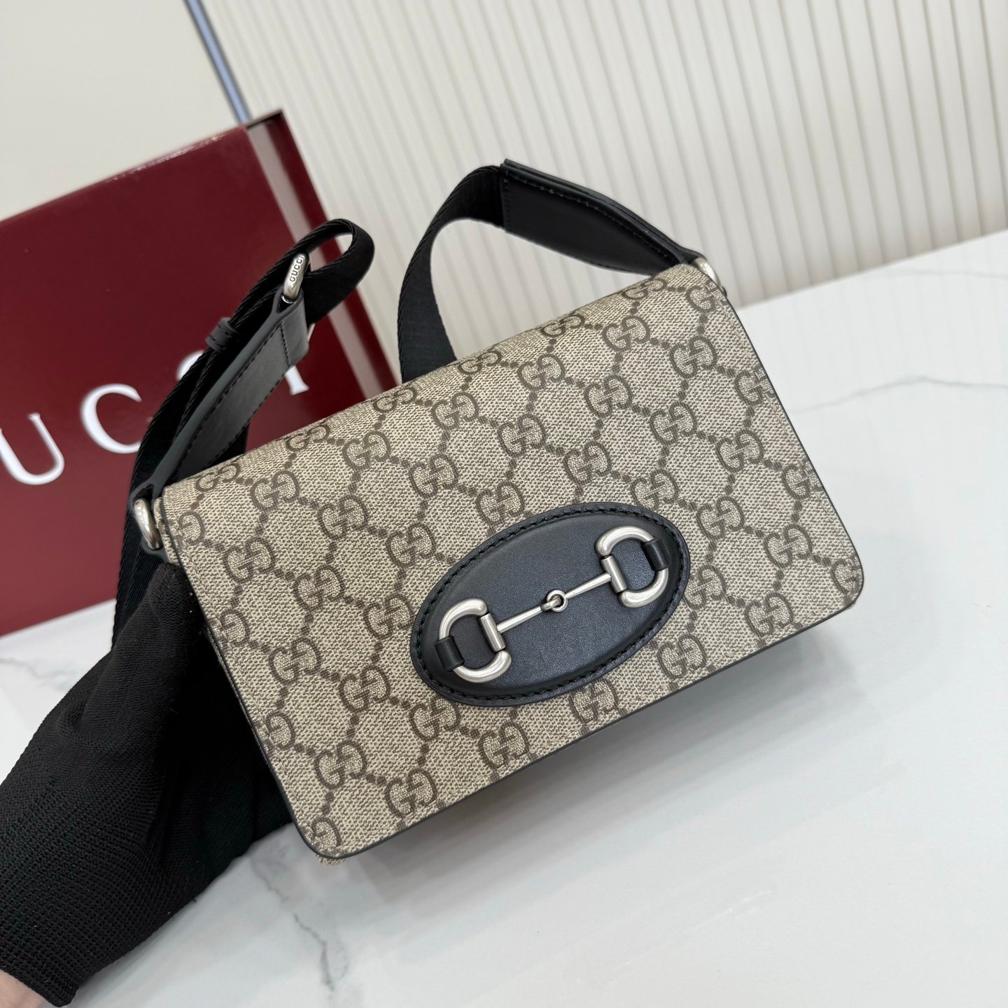 Gucci Horsebit 1955系列推出一款方形剪裁迷你手袋。这款手袋专为收纳常用小物打造，黑色皮革滚边和银色调配件散发别致情调。