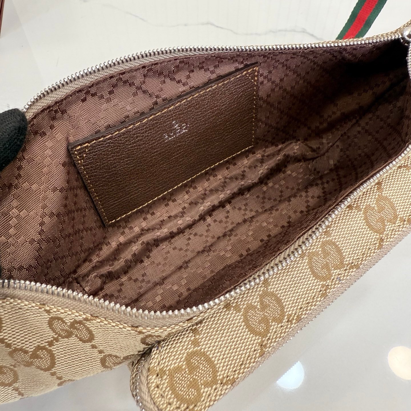 这件单品出自Gucci Primavera系列。Gucci Tag系列的设计同步城市节奏。经典GG帆布面料贯穿于多功能迷你手袋的廓形设计中，并缀饰“Gucci Made in Italy”金属标签，令整款单品更加精致。