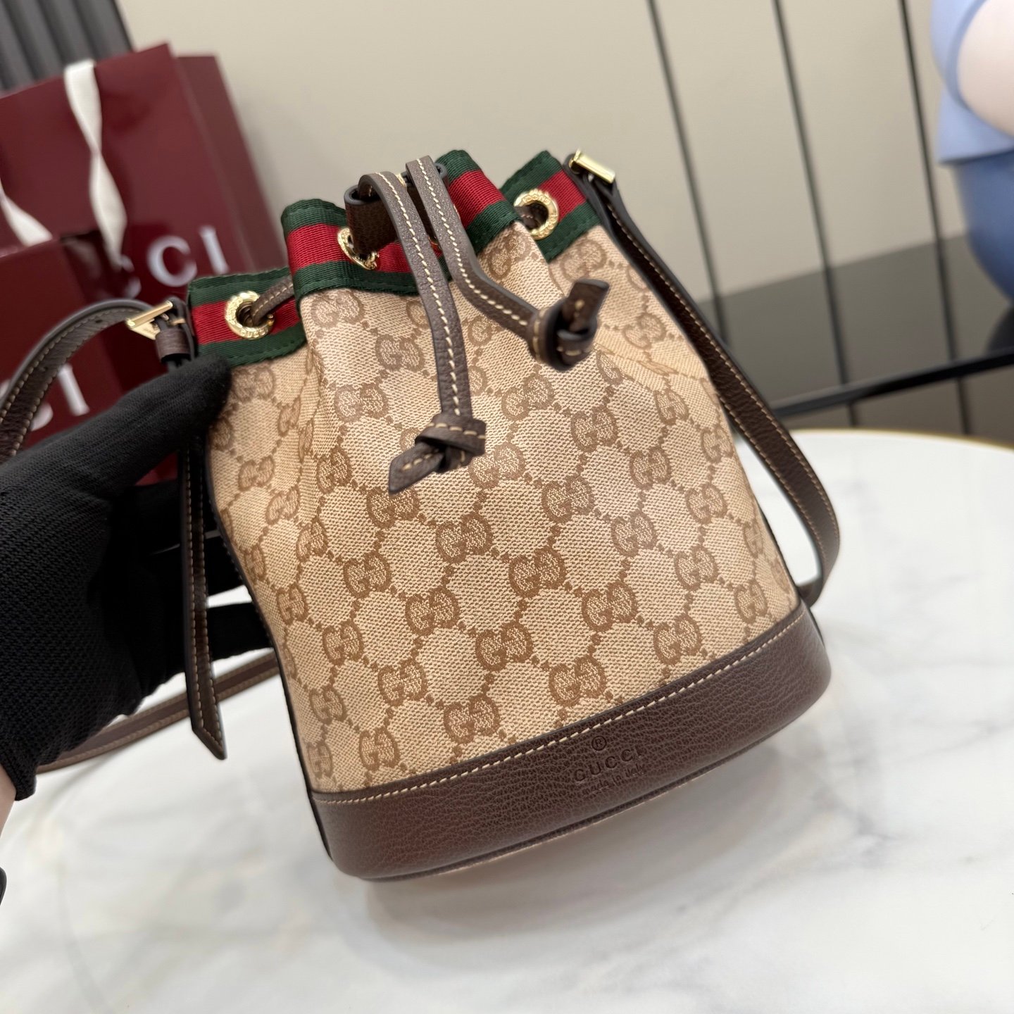 配全套原厂专柜包装 Generation Gucci古驰世代系列深入探索品牌的典藏元素，将不同世代的设计融合为统一的美学叙事。GG涂层帆布搭配经典织带，为多功能小型皮具带来标志性风格，如这款设计用于存放日常必需品的水桶包。