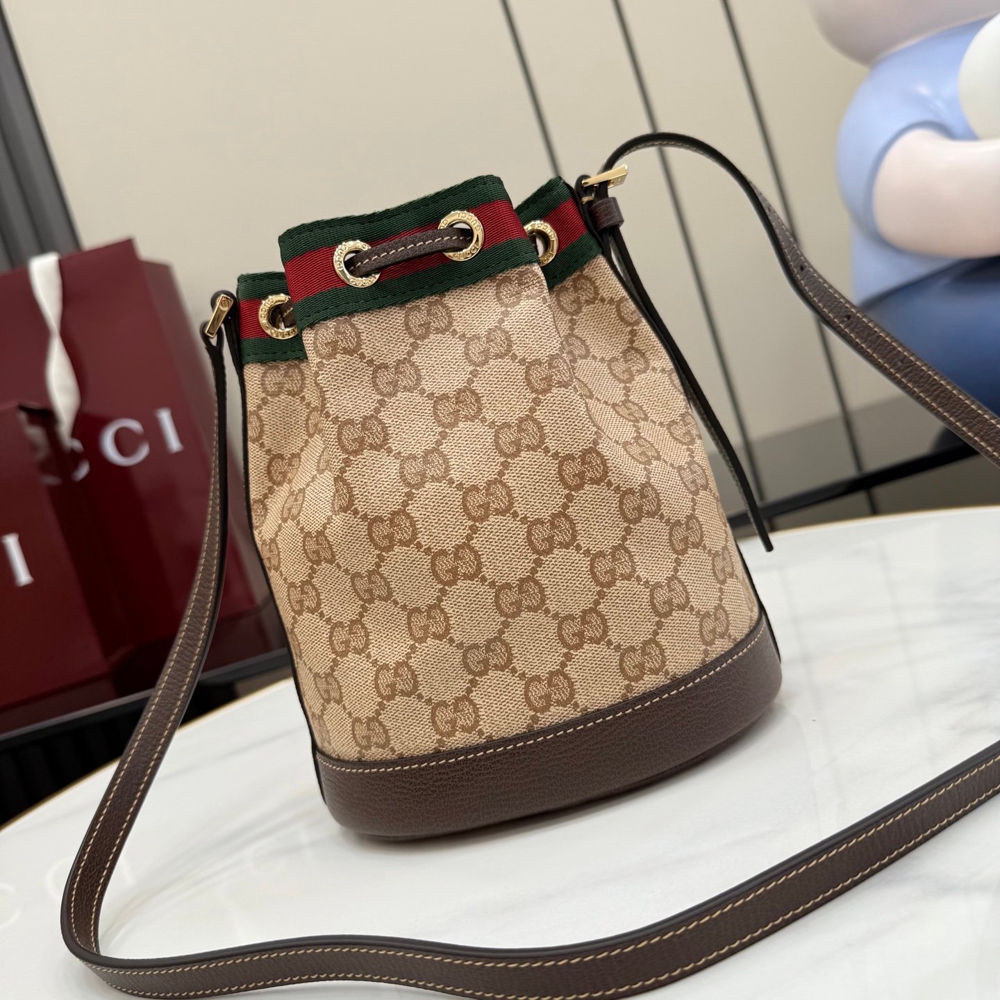 配全套原厂专柜包装 Generation Gucci古驰世代系列深入探索品牌的典藏元素，将不同世代的设计融合为统一的美学叙事。GG涂层帆布搭配经典织带，为多功能小型皮具带来标志性风格，如这款设计用于存放日常必需品的水桶包。