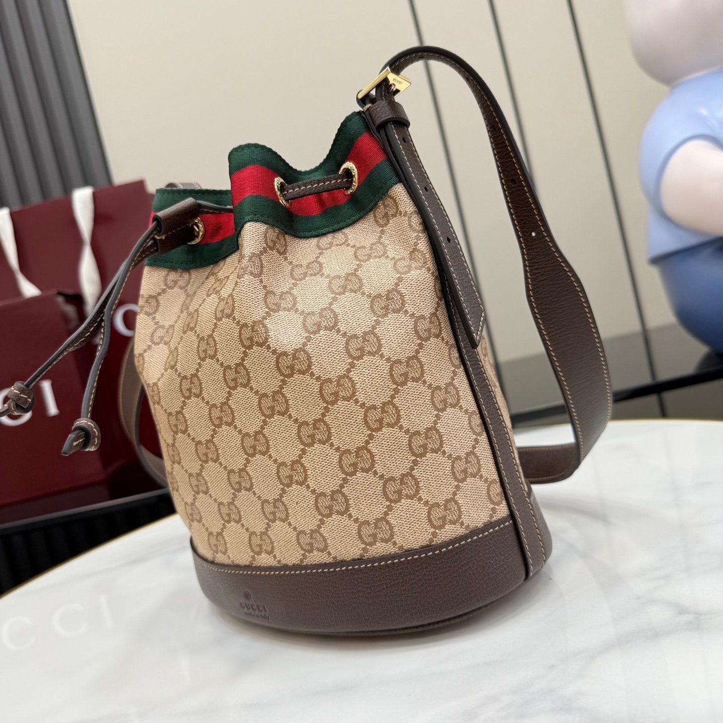 配全套原厂专柜包装 Generation Gucci系列深入探索品牌的经典元素,将不同世代的设计融合成一种美学叙事。GG涂层帆布搭配织带,为多功能小型皮具带来品牌标志性的设计,例如这款设计用于存放日常必需品的水桶包。