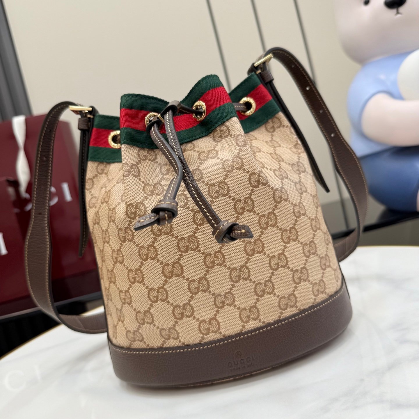 配全套原厂专柜包装 Generation Gucci系列深入探索品牌的经典元素,将不同世代的设计融合成一种美学叙事。GG涂层帆布搭配织带,为多功能小型皮具带来品牌标志性的设计,例如这款设计用于存放日常必需品的水桶包。