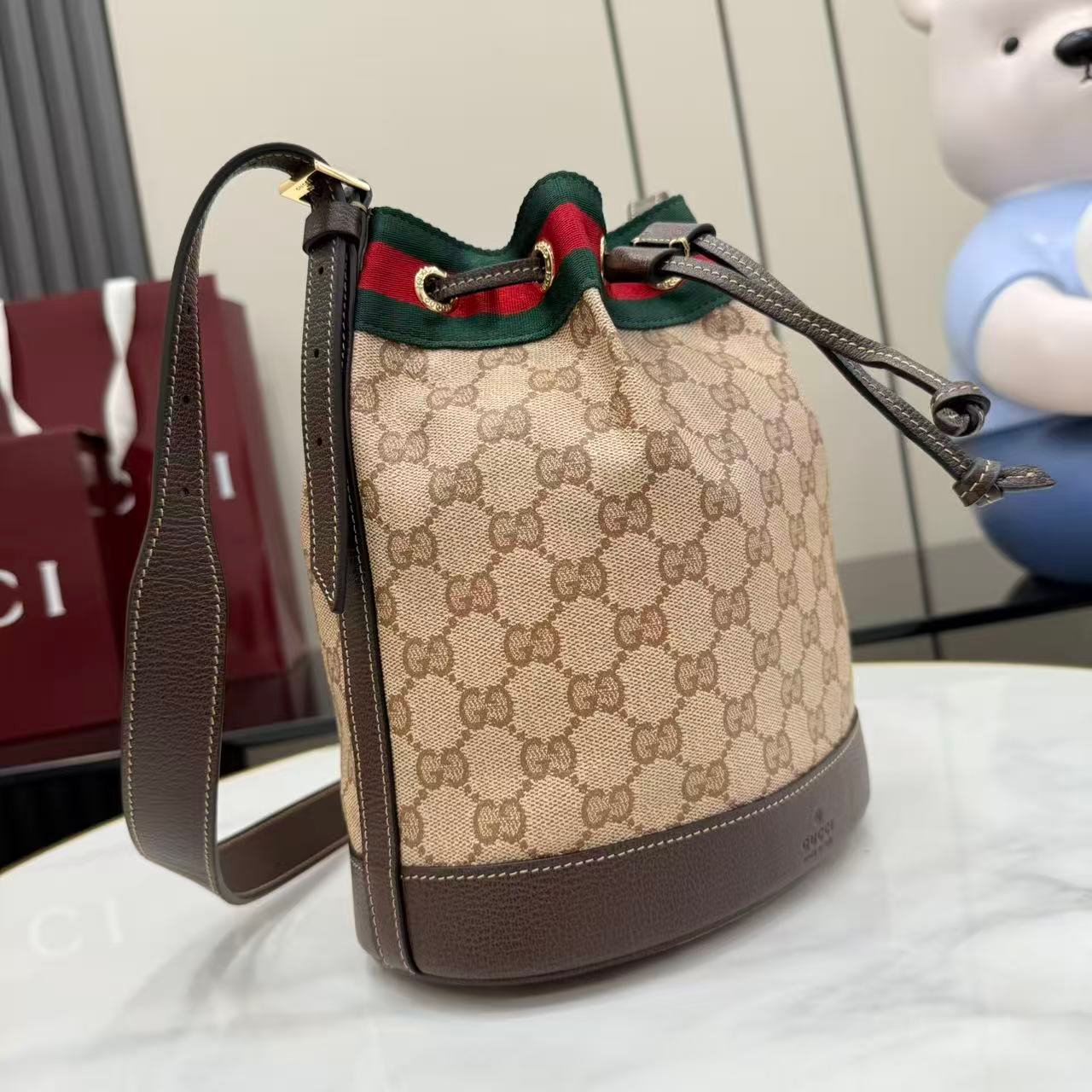 配全套原厂专柜包装 Generation Gucci系列深入探索品牌的经典元素,将不同世代的设计融合成一种美学叙事。GG涂层帆布搭配织带,为多功能小型皮具带来品牌标志性的设计,例如这款设计用于存放日常必需品的水桶包。