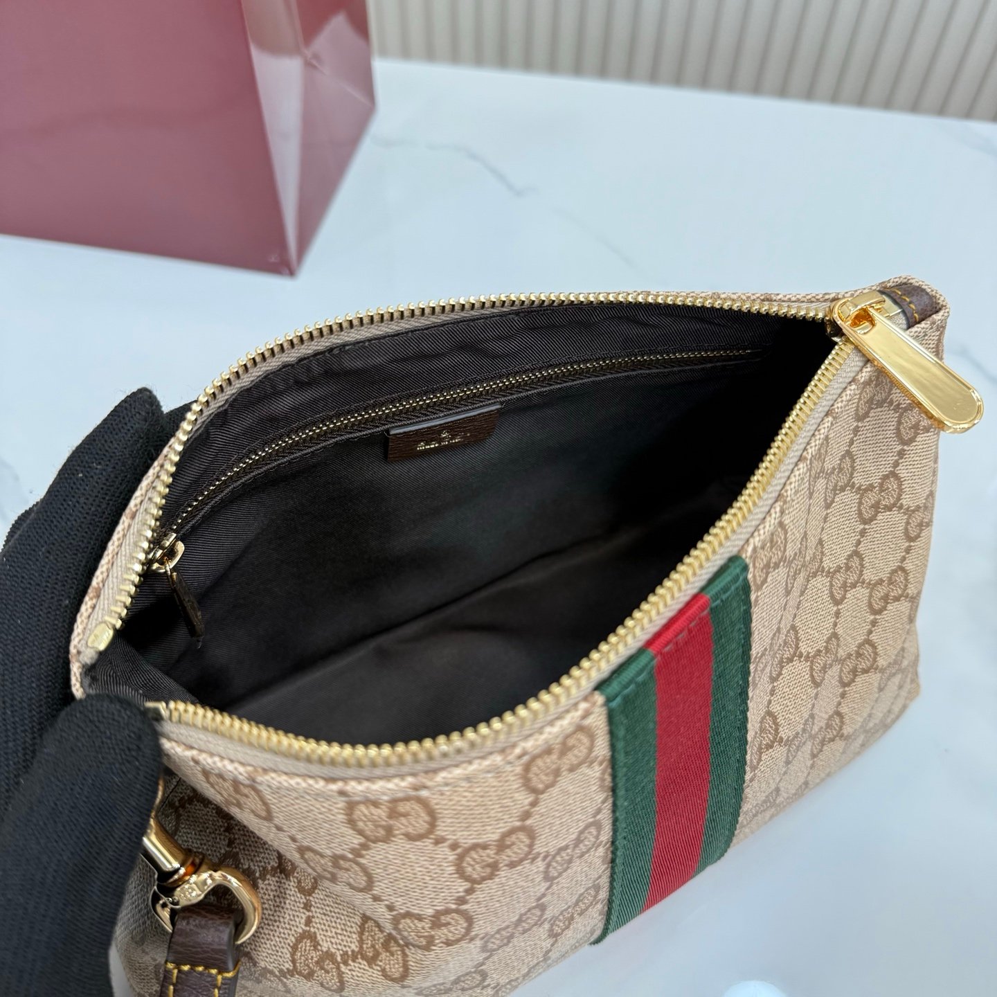 Generation Gucci古驰世代系列深入探索品牌的典藏元素，将不同世代的设计融合为统一的美学叙事，推出全新小皮具系列，以GG涂层帆布为基础，饰有显眼的织带细节。搭配皮革滚边，这款多功能款式采用无衬里设计，呈现出时尚轻盈的外观。
