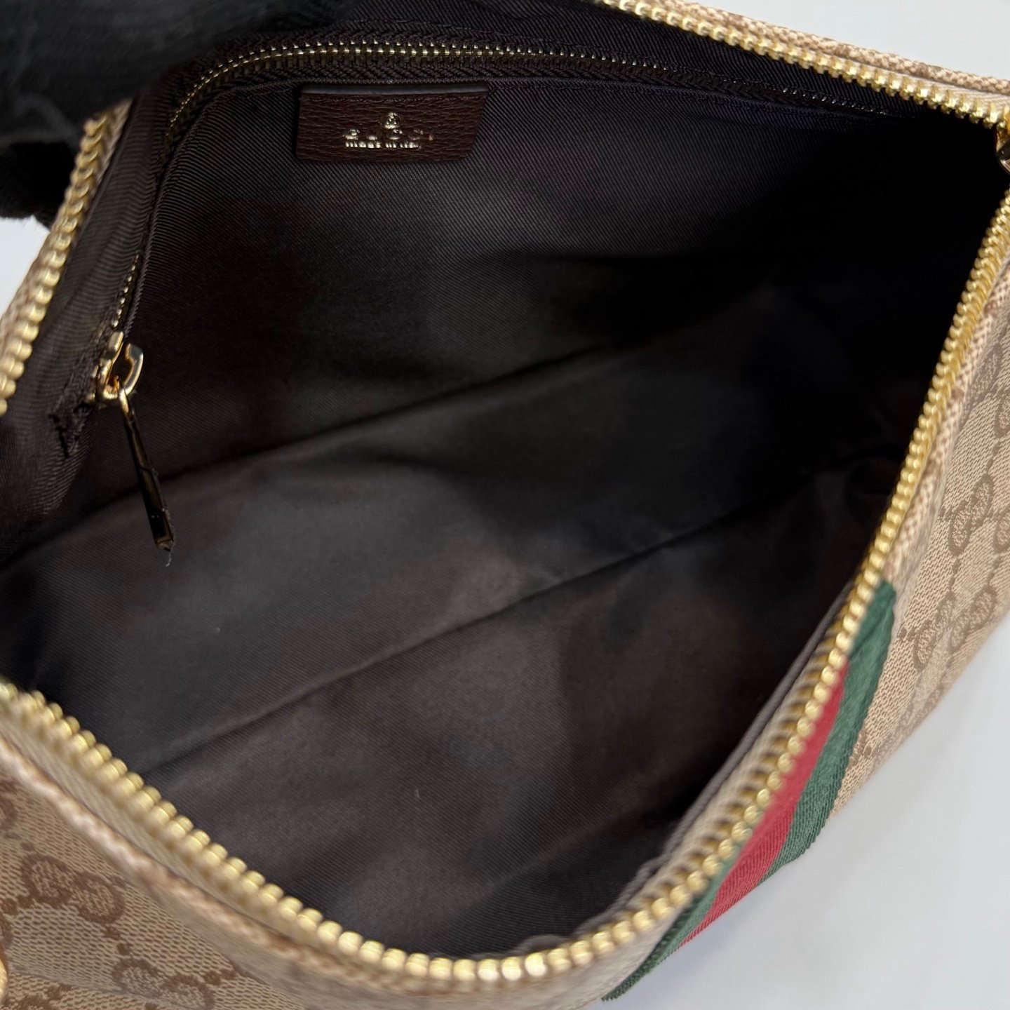 Generation Gucci古驰世代系列深入探索品牌的典藏元素，将不同世代的设计融合为统一的美学叙事，推出全新小皮具系列，以GG涂层帆布为基础，饰有显眼的织带细节。搭配皮革滚边，这款多功能款式采用无衬里设计，呈现出时尚轻盈的外观。