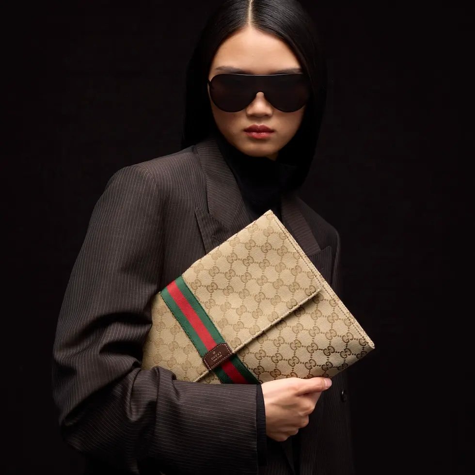Generation Gucci系列深入探索品牌的典藏元素，将不同世代的设计融合成一种美学叙事。这款手拿包采用GG帆布制作，并饰有织带，是公文包的理想替代品。